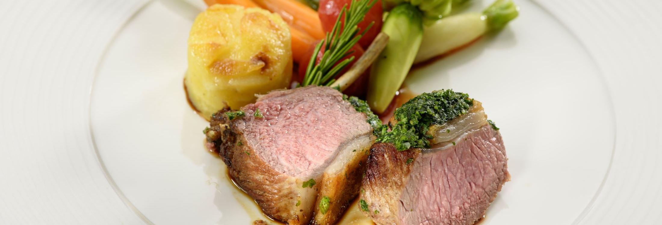 Zart rosa gebratenes Kräuterlamm mit Gemüse, Rosmarinzweig und gratiniertem Kartoffelrösti auf weißem Teller – serviert im Romantik Hotel | Restaurant Hirsch in Sonnenbühl-Erpfingen auf der Schwäbischen Alb