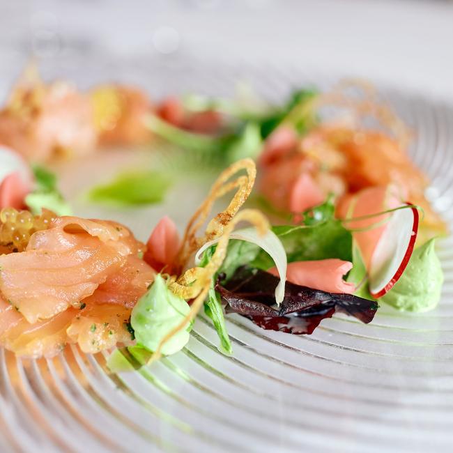 Fein angerichtetes Lachsgericht mit frischem Gemüse und dekorativen Elementen im Romantik Hotel | Restaurant Hirsch auf der Schwäbischen Alb