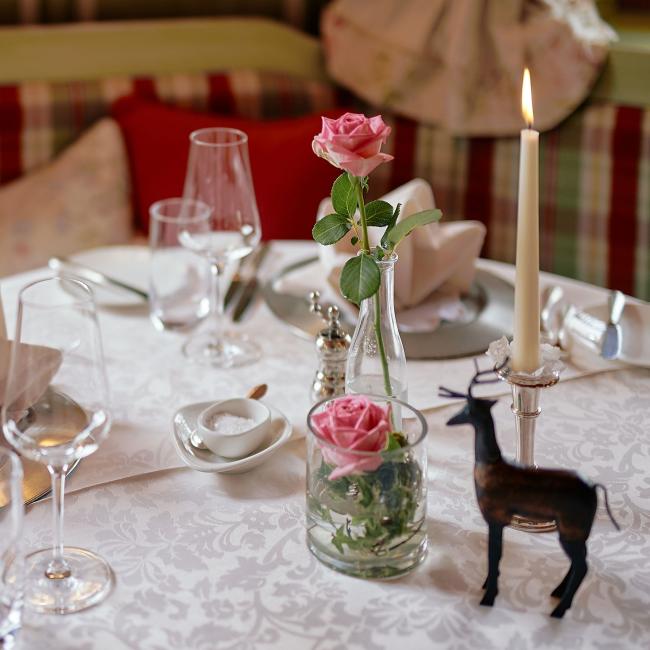Festlich gedeckter Tisch mit Kerze, Rosendekoration und Hirschfigur im Romantik Hotel | Restaurant Hirsch auf der Schwäbischen Alb