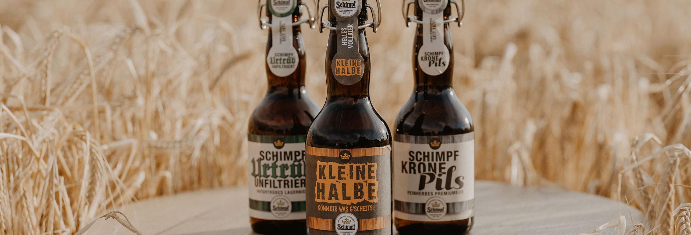 Drei Bierflaschen auf einem Holzfass vor einem goldenen Getreidefeld im Romantik Hotel | Restaurant Hirsch auf der Schwäbischen Alb